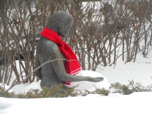 bronze statue in the garden snow has a scarf today
