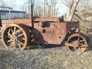 steamroller at rest on the roadside rusting away..
