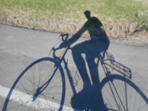 late afternoon I ride along a quiet road with my shadow...